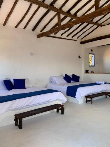 two beds in a white room with wooden ceilings at Refugio en Barichara con piscina, jardines y atardeceres únicos in Barichara
