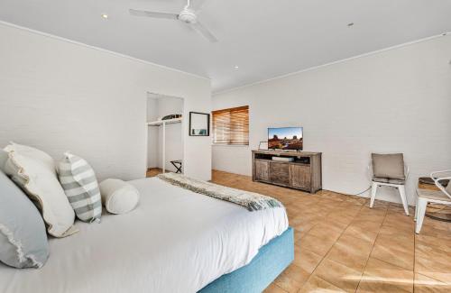 a white bedroom with a bed and a television at The Ranch Hunter Valley - central to all the Hunter Valley has to offer in Pokolbin