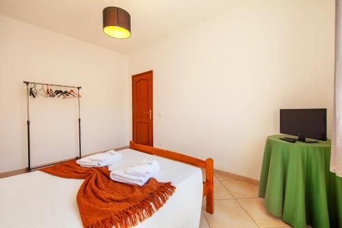a bedroom with a bed with a green table and a television at FF - Sea Breeze Guesthouse in Lagos