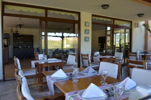 ein Restaurant mit Holztischen und -stühlen und Fenstern in der Unterkunft Ada Adrasan Hotel in Kumluca