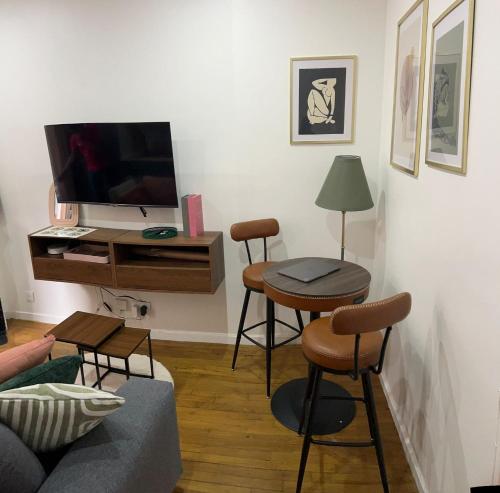 a living room with a tv and two stools at Chic & Comfort Suresnes-Paris in Suresnes