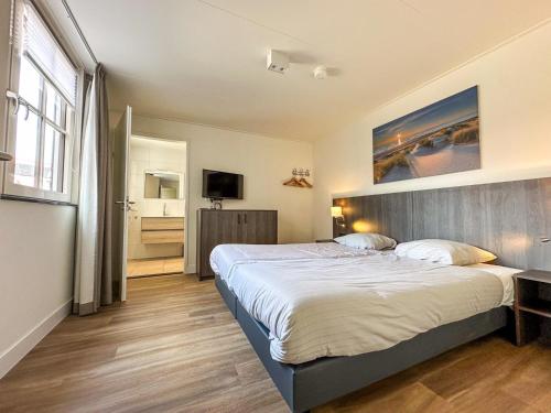 Un dormitorio con una cama grande y un televisor. en Coast and Calm 57, en Colijnsplaat