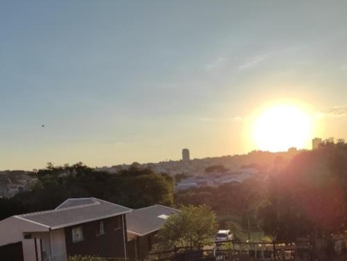 a sunset over a house with the sun in the background at Pousada Apucarana - Sede in Apucarana