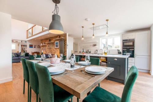 a kitchen and dining room with a wooden table and green chairs at The Old School Hall - Opulence and Location in Kent
