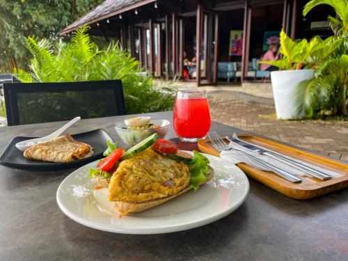 a table with a plate of food and a drink at Houttuyn Wellness River Resort in Paramaribo
