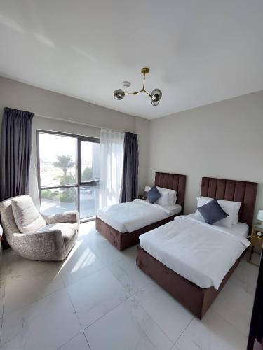 a bedroom with two beds and a chair and a window at Budget-friendly 2bd near EXPO with a huge pool in Dubai