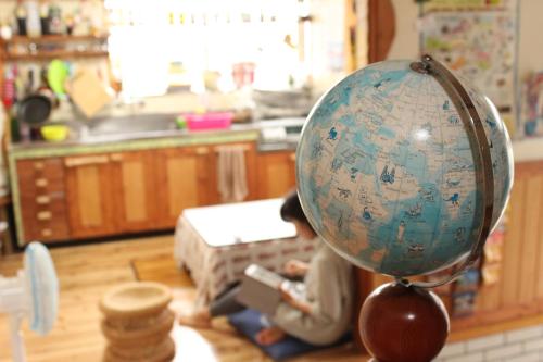a small doll sitting on the floor with a globe at Katsuo Guest House in Kochi