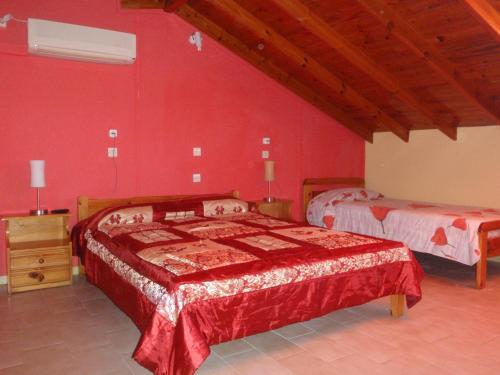 a bedroom with two beds and a red wall at Kate Apartments in Kokkari