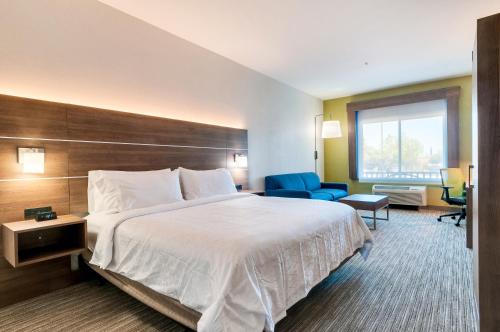 a hotel room with a large bed and a blue chair at Holiday Inn Express Hotel & Suites Banning by IHG in Banning