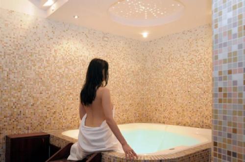 Hotel Ariston Imperial في بورتو غاريبالدي: امرأة جالسة في حوض الاستحمام في الحمام