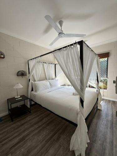 a bedroom with a white bed with a ceiling fan at Nature's Nest - Pool - SPA - Outdoor Kitchen and Dining in Leanyer