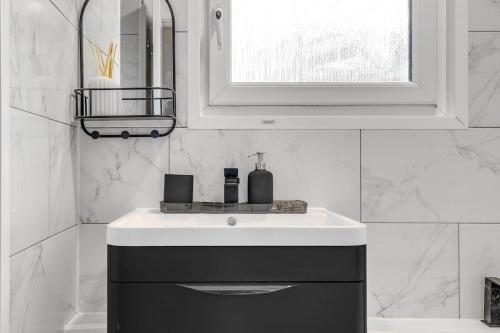 Un baño blanco con lavabo y espejo. en Modern Apartment Zone 1, 2 Bed Sleeps 6 with Balcony in Central London - Open for Families Relocating, Business Stay, and Long Stay, en Londres
