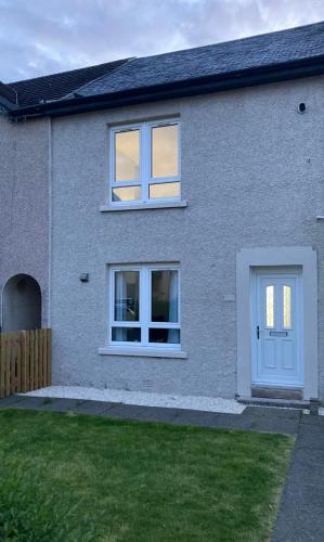 a gray house with a white door and a yard at Modern and stylish 3 bedroom 2 bathroom west end house with Free WiFi and parking in Scotstoun West Station