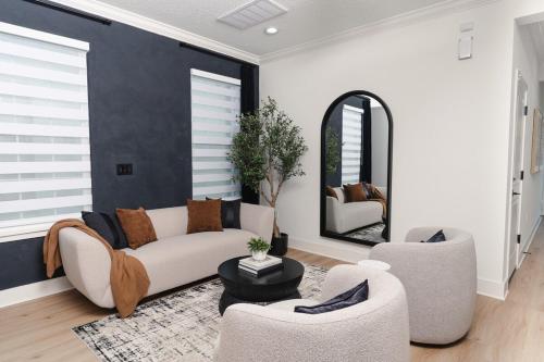 a living room with a couch and two chairs and a mirror at 3BR-3BA Modern Ybor Central Tampa with Rooftop Firepit & 2 Bikes-Fully Equipped in Tampa