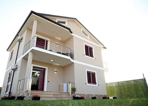 a white house with a porch and stairs at Fly Rooms in Krujë