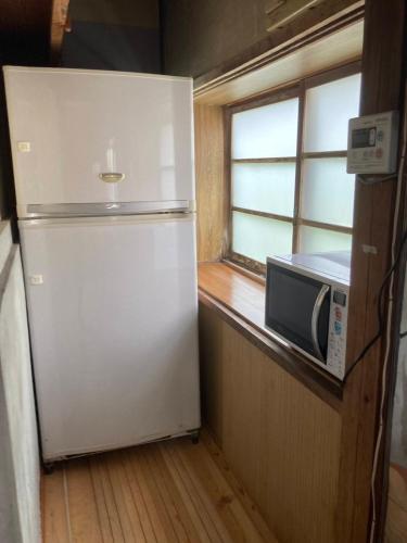 a white refrigerator in a kitchen with a microwave at Yado KONAMI in Shimoda
