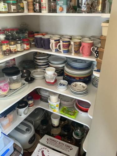 a pantry filled with lots of dishes and plates at Tamaterau Seaview House in Whangarei in Whangarei