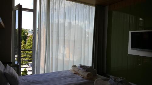 a bedroom with a window with a bed and a television at Hotel Zena Beauty & Shopping Center in Hévíz