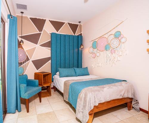 a bedroom with a bed and a blue chair at LA QUEBRADA ECO LODGE Hotel Boutique in Potrero