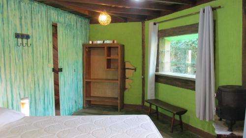a bedroom with green walls and a bed and a window at Pousada Alquimia in Aiuruoca
