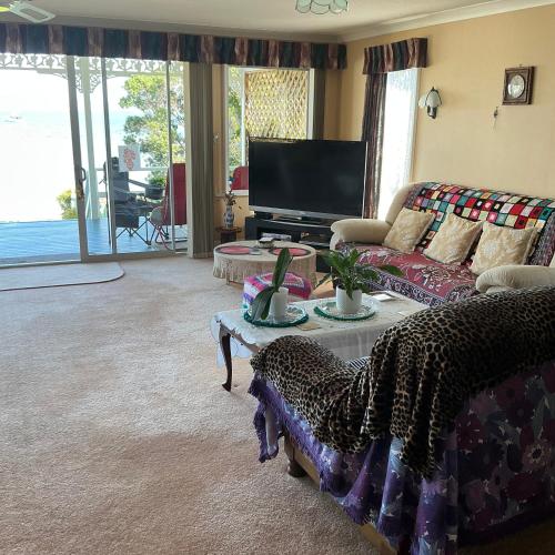 a living room with a couch and a tv at Tamaterau Seaview House in Whangarei in Whangarei