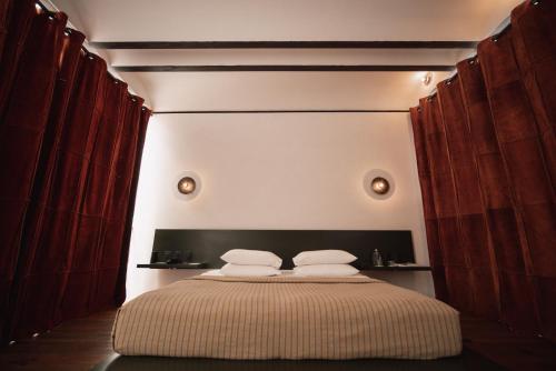 a bedroom with a large bed with red curtains at Otro Oaxaca, a Member of Design Hotels in Oaxaca City