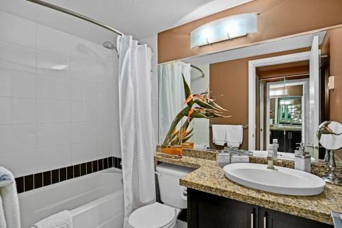 a bathroom with a sink and a toilet and a tub at Luxury 2BR Designer Apartment - Prime Downtown Location! in Vancouver