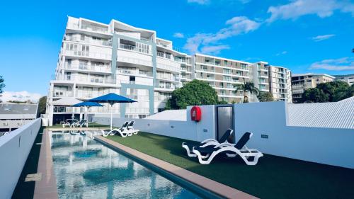 a swimming pool with lounge chairs and a building at Scarborough Beach Resort Brisbane in Scarborough
