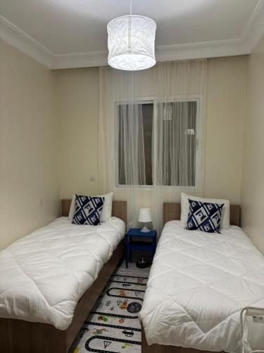 a room with two beds and a chandelier at Apprt 2min de la Gare,Wi-Fi Fibre, Netflix ,PS4 in Settat