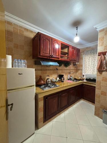 a kitchen with wooden cabinets and a white refrigerator at Apprt 2min de la Gare,Wi-Fi Fibre, Netflix ,PS4 in Settat