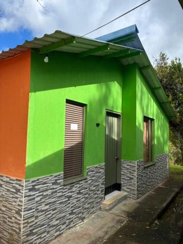 a green and orange building with a door at Cabañas Gachalá - Centro vacacional El jazmín in Gachalá