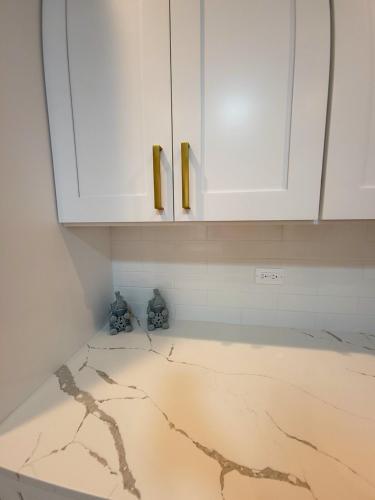 a kitchen with white cabinets and a marble floor at Beautiful 4 bedroom 2 bathroom apartment near everything in Chicago