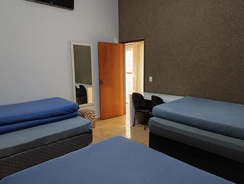a room with two beds and a chair and a door at Casa dos Carvalhos Rua do sabiá 25 coab 1 in Olímpia