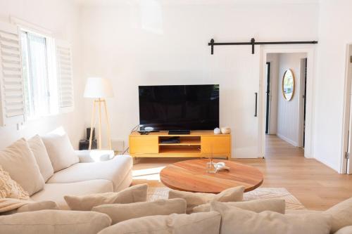 a living room with a white couch and a table at Beautiful Queenslander Getaway in Brisbane