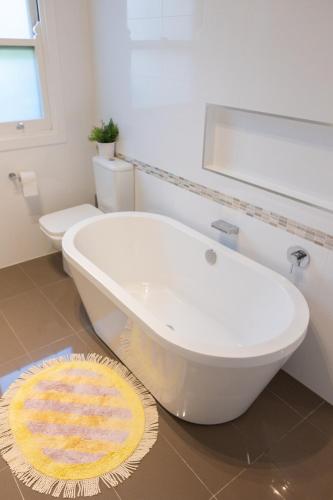 a white bathroom with a tub and a toilet at Beautiful Queenslander Getaway in Brisbane