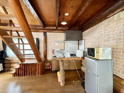 a kitchen with a refrigerator and a counter with a microwave at 貸別荘はこぶね -Vacation rental Hakobune- in Yufu