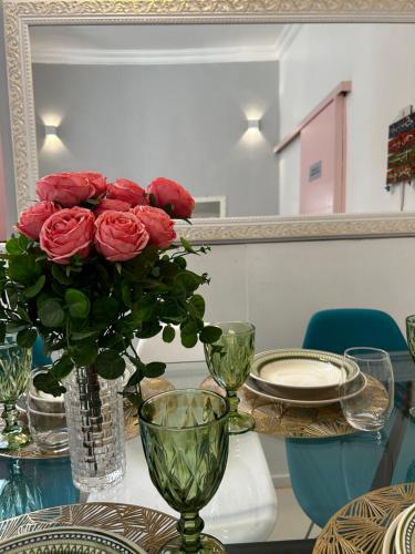 a table with a vase with red roses in it at Casarão para 16 pessoas in Rio de Janeiro