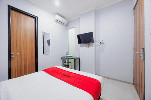 a bedroom with a white bed and a television at RedDoorz Plus near Radio Dalam 3 in Jakarta