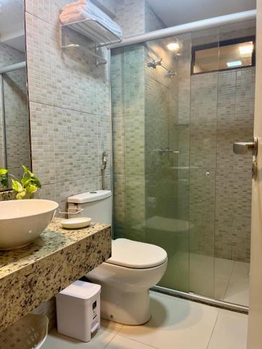 a bathroom with a toilet and a glass shower at Brisas Tropical Flat in Conde