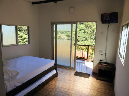 ManaureにあるEl Tucán Ecolodge Manaureのベッドルーム1室(ベッド1台付)、バルコニー付きのスライドドアが備わります。