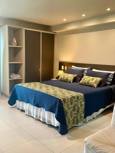 a bedroom with a large bed with blue sheets and pillows at Brisas Tropical Flat in Conde