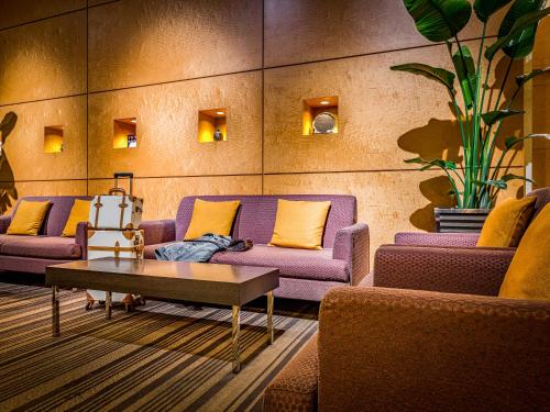 a living room with purple couches and a table at Mitsui Garden Hotel Okayama in Okayama