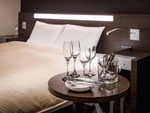 a table with four wine glasses on a bed at Mitsui Garden Hotel Okayama in Okayama