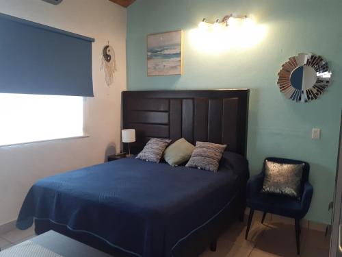 a bedroom with a blue bed and a chair at Le Petit Oasis a few steps from the Beach in Peñita de Jaltemba
