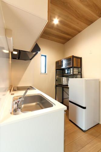 a kitchen with a sink and a white refrigerator at ホテルトレーラーシップガーデン阿蘇 in Aso