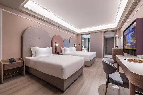a hotel room with two beds and a desk at Mercure Jingjiang Downtown in Jingjiang