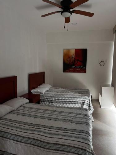 a bedroom with two beds and a ceiling fan at Gran Palma Residencial in Acapulco