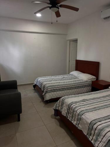a bedroom with two beds and a ceiling fan at Gran Palma Residencial in Acapulco