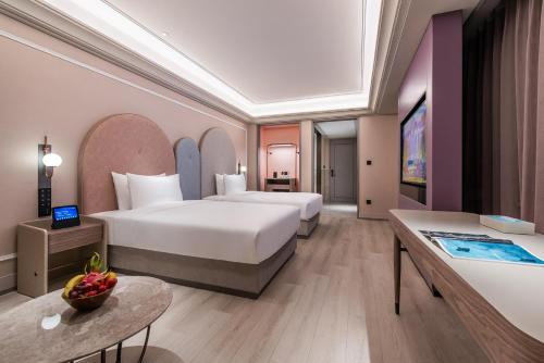 a hotel room with two beds and a television at Mercure Jingjiang Downtown in Jingjiang