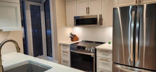 a kitchen with a stainless steel refrigerator and a sink at Mountain view chalet avec vue sur la montagne in Stoneham